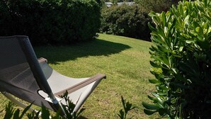 Zona verde con una silla de descanso, vista a una montaña y un cuerpo de agua al fondo.