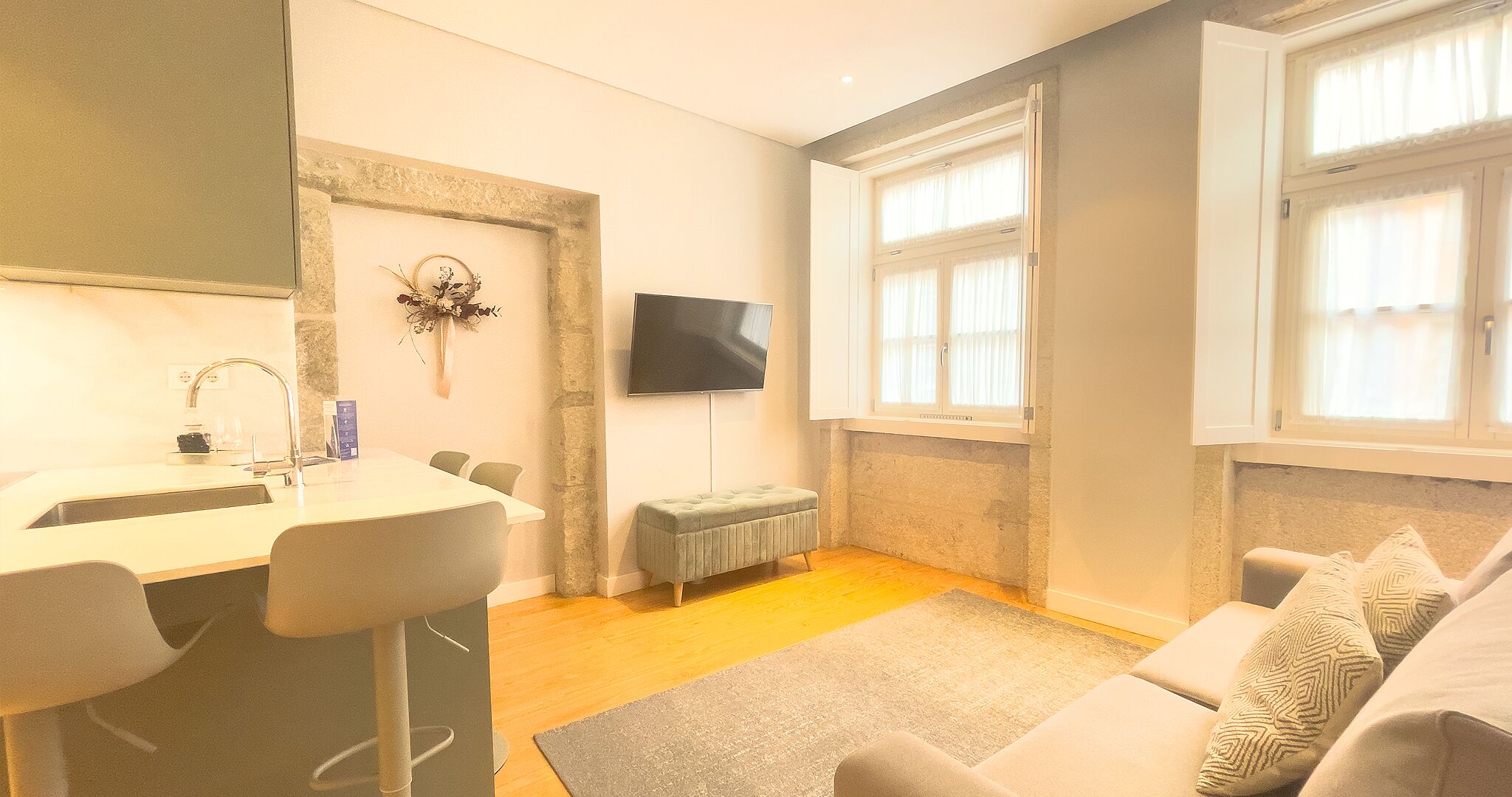 Ein modernes Wohnzimmer mit einer Couch, einem kleinen Tisch und einem an der Wand befestigten Fernseher.
