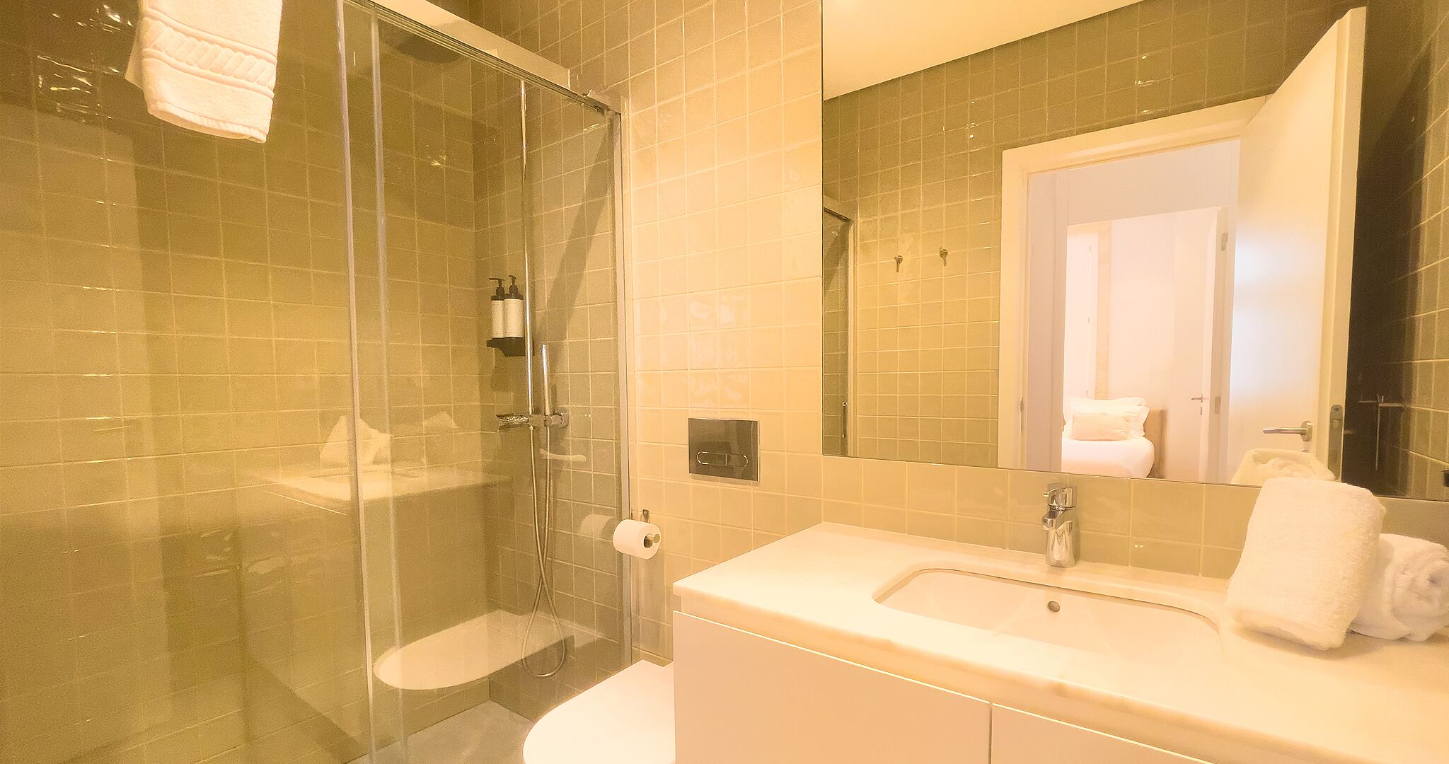 A bathroom with a glass-enclosed shower, a white sink, and a mirror reflecting the room.