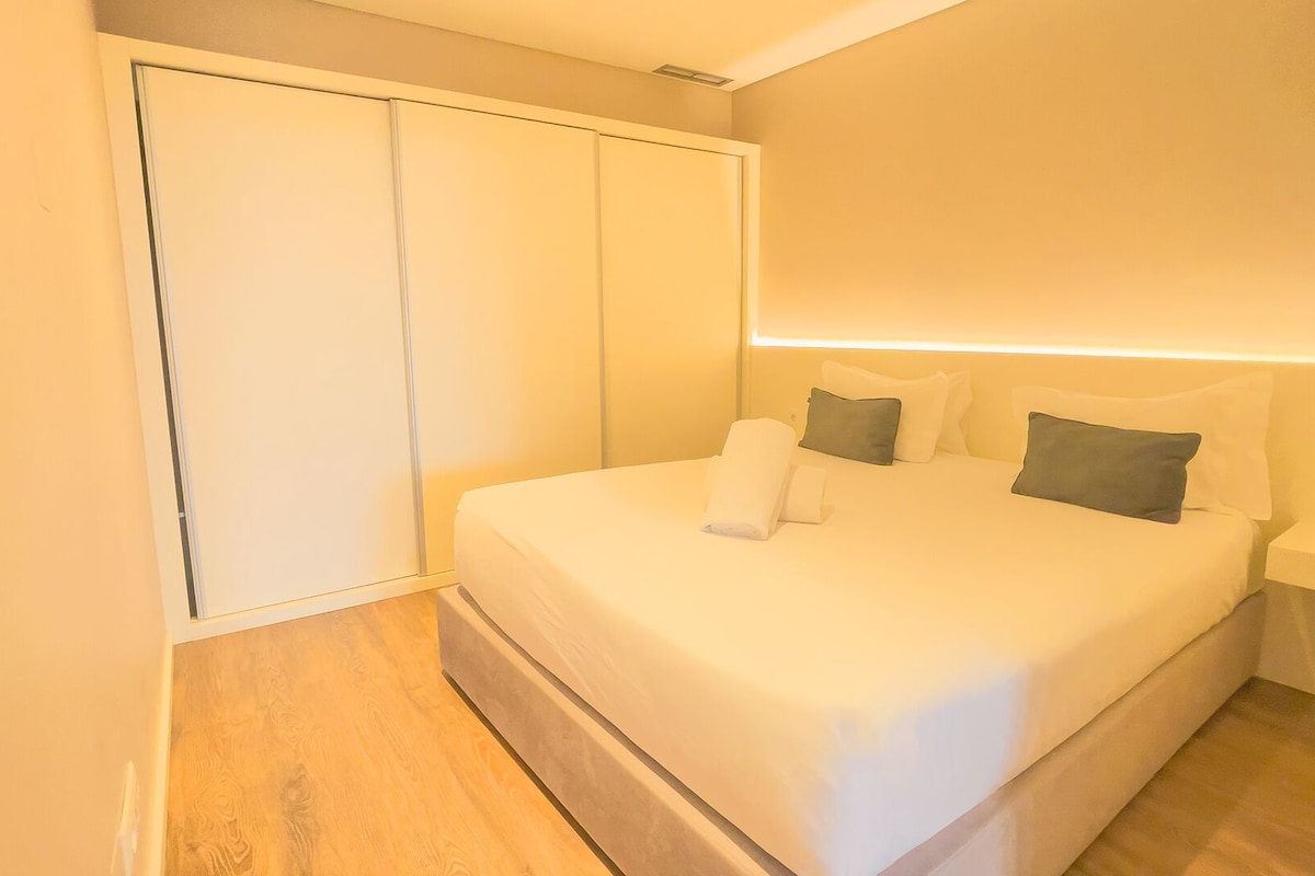 Ein Schlafzimmer mit Bett, Kissen, Nachttisch und Kleiderschrank.