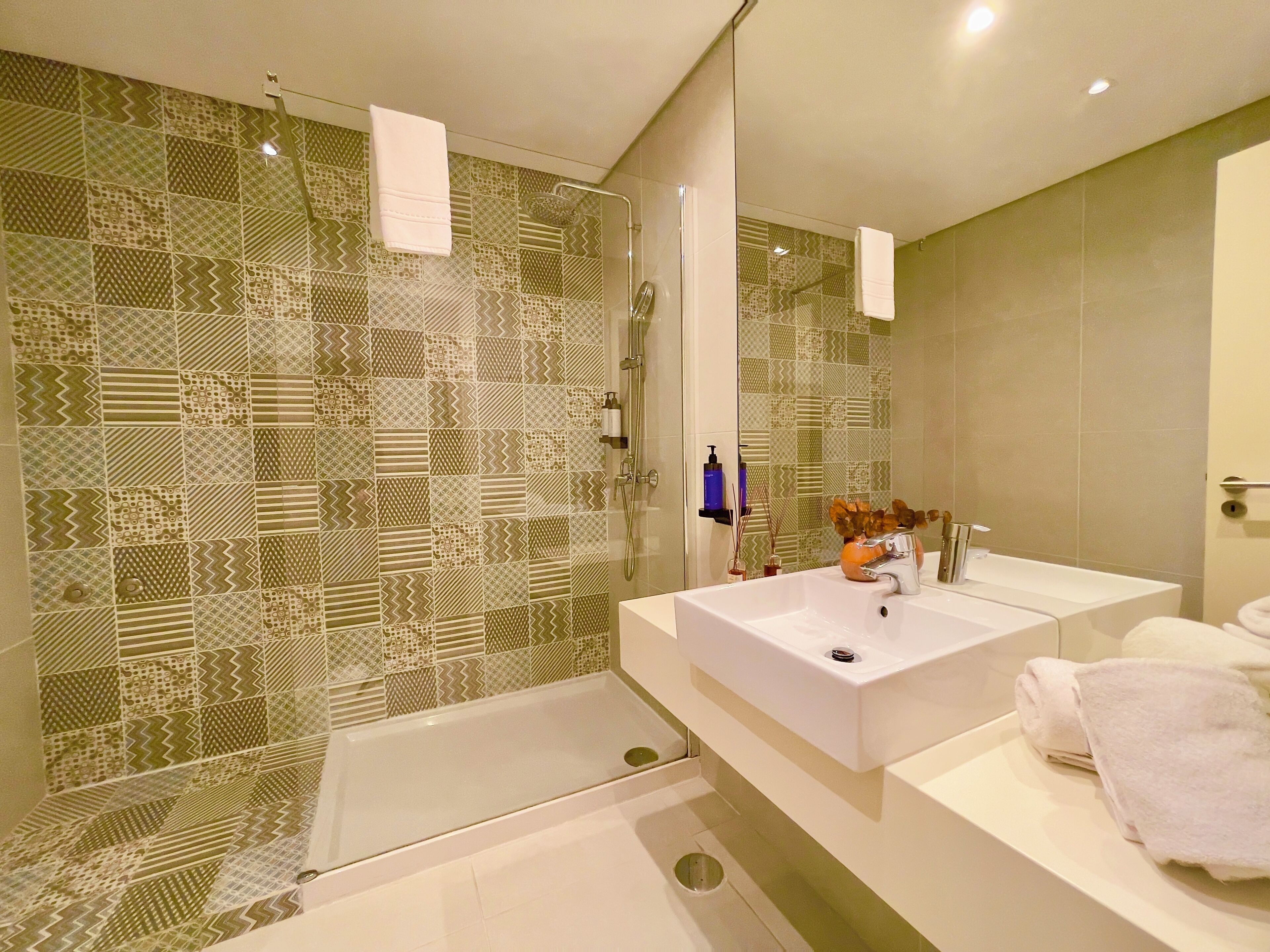 A modern bathroom with a glass shower enclosure, a white sink, and a large mirror.
