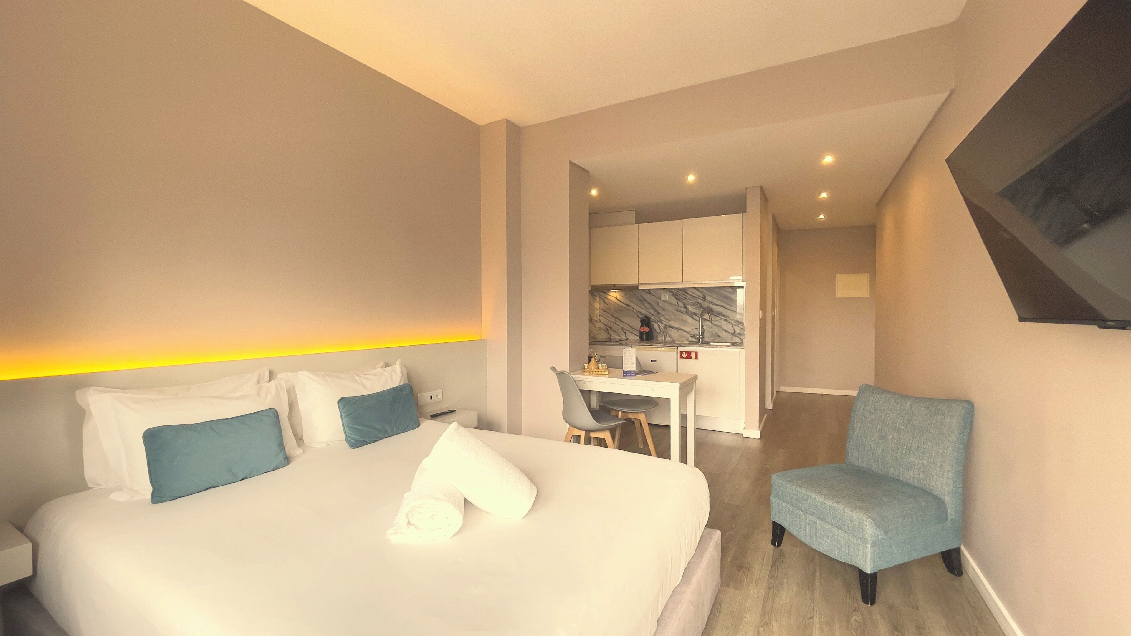 A hotel room with a bed, a desk, and a chair.