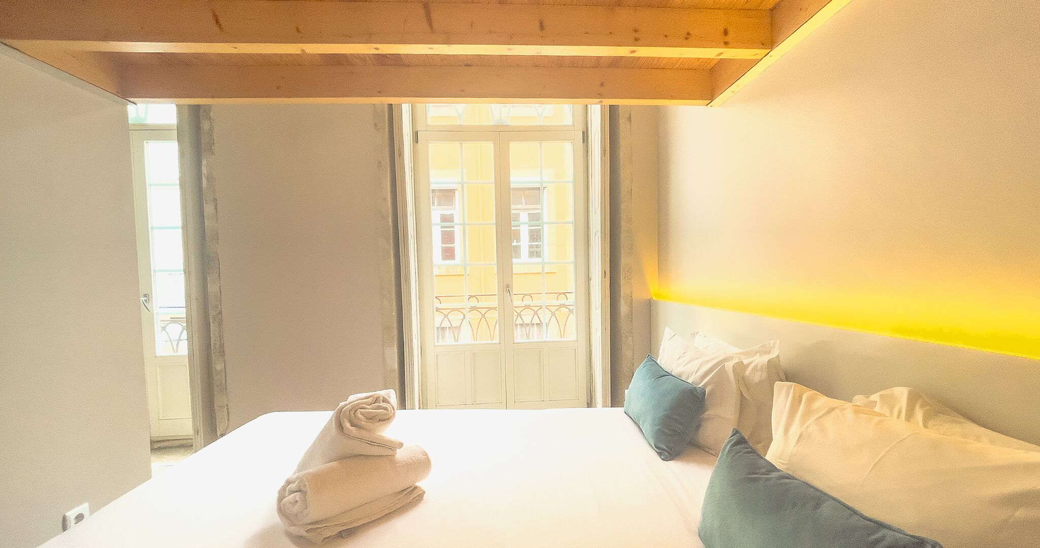 Un dormitorio con cama, almohadas, ventana y balcón.