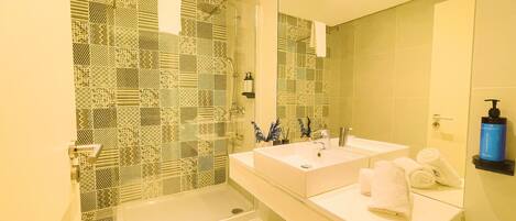 A modern bathroom with patterned tiles, a dual sink vanity, a bathtub, and a large mirror.
