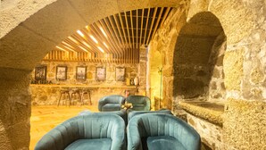Zona bar con pareti in pietra, travi in legno al soffitto, sedute imbottite blu e camino in pietra.