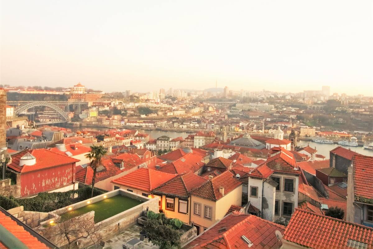 A cityscape with red-roofed buildings, a bridge, and a river.