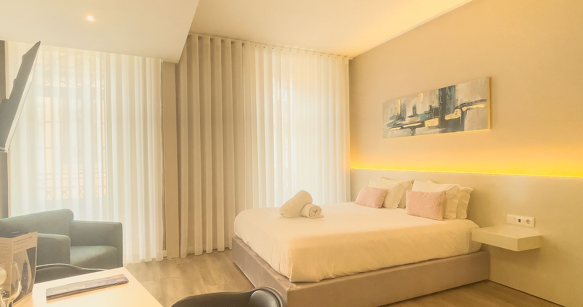 Ein modernes Hotelzimmer mit einem großen Bett, einem Schreibtisch mit Stuhl und einem Bild an der Wand.