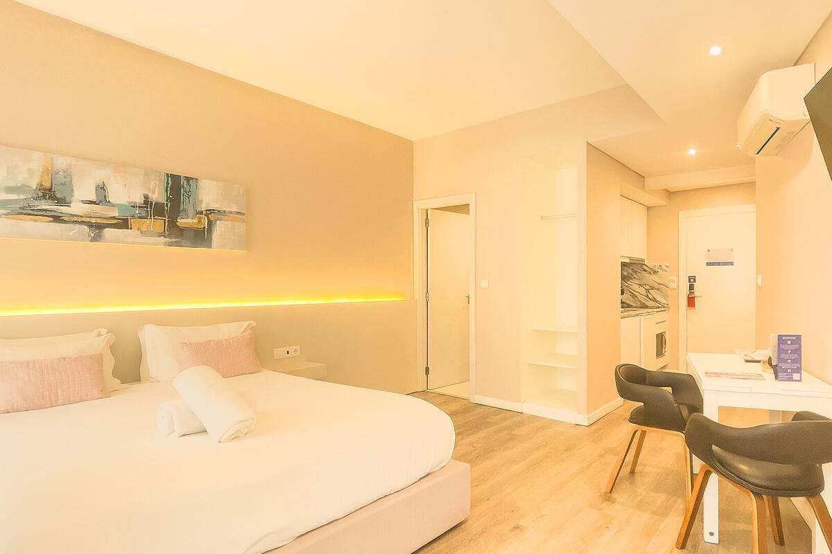 A modern hotel room with a large bed, bedside tables, a desk, and a chair.
