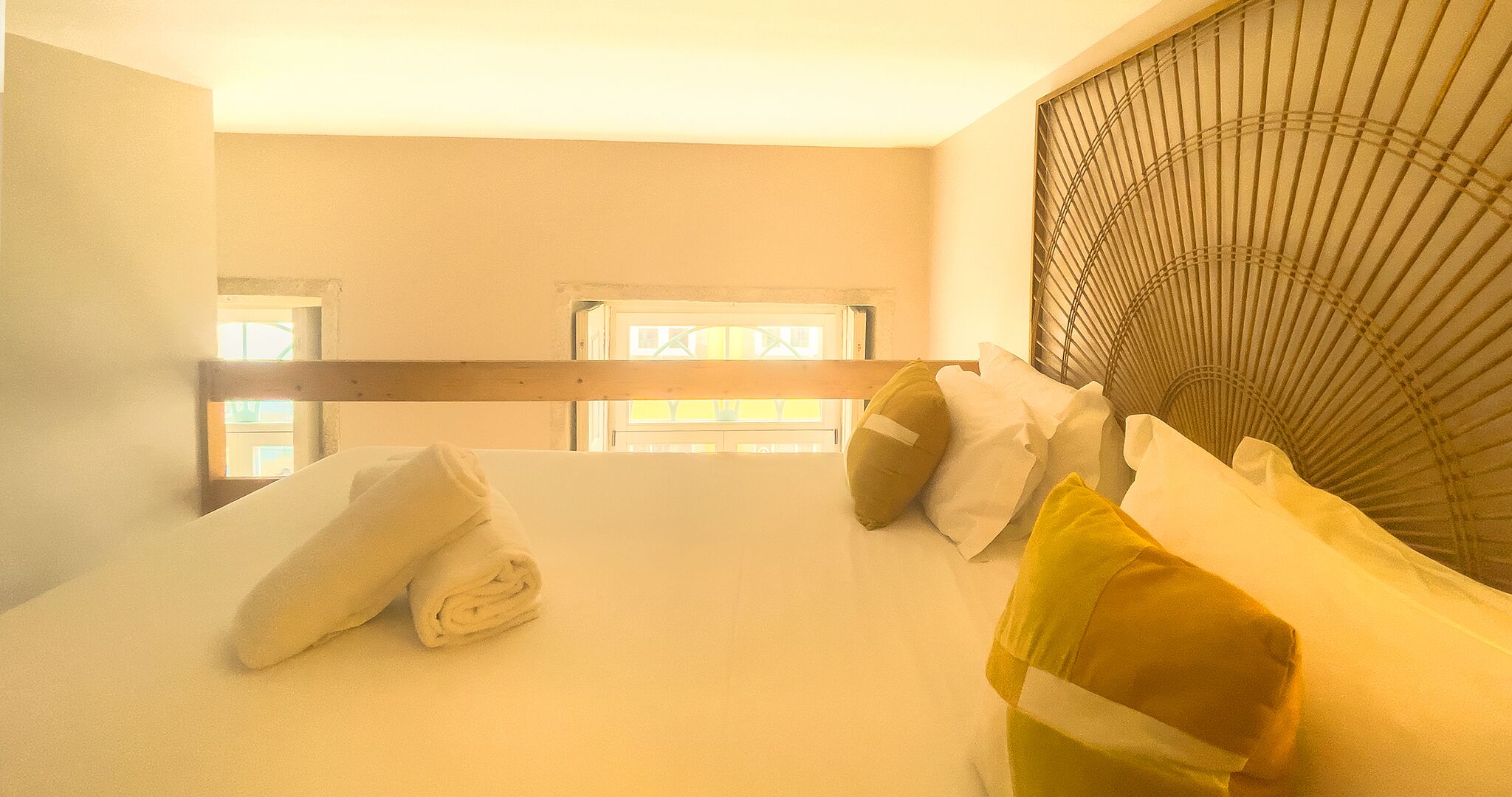 Habitación de hotel con cama, almohadas y ventana con persianas.