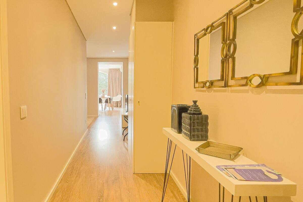 A hotel hallway with a bathroom on the left, a dining area in the center, and a reception desk on the right.