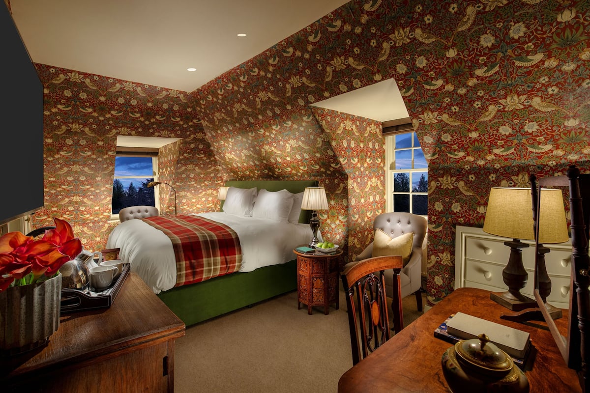 A bedroom with a bed, a chair, a nightstand, and a dresser.