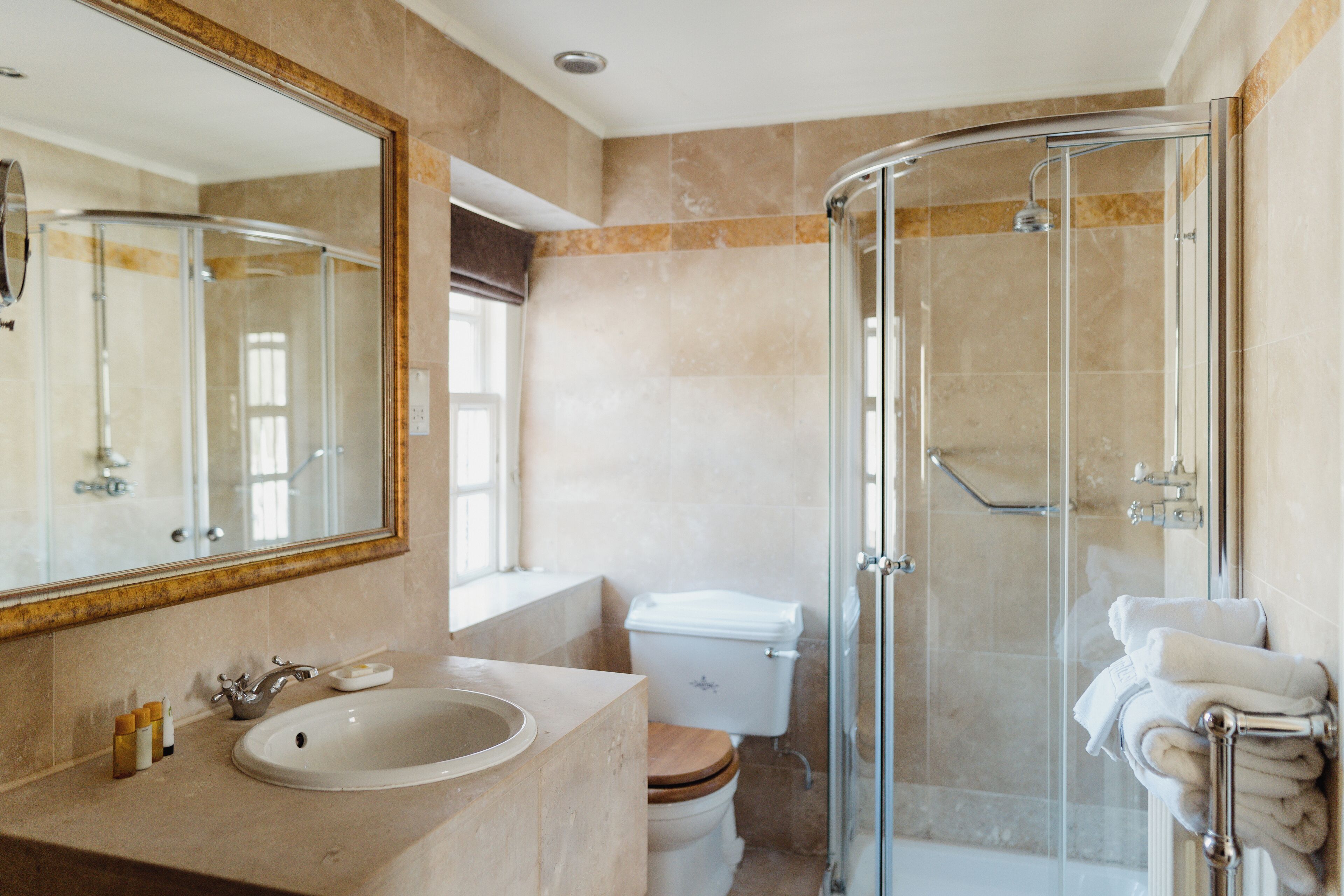 A modern bathroom with a glass-enclosed shower, a sink with a wooden vanity, and a toilet.