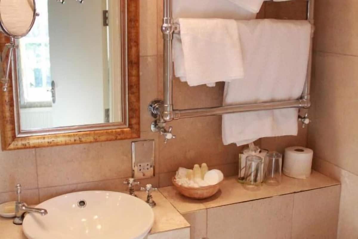 A bathroom with a round sink, a mirror, a towel rack, and a toilet.