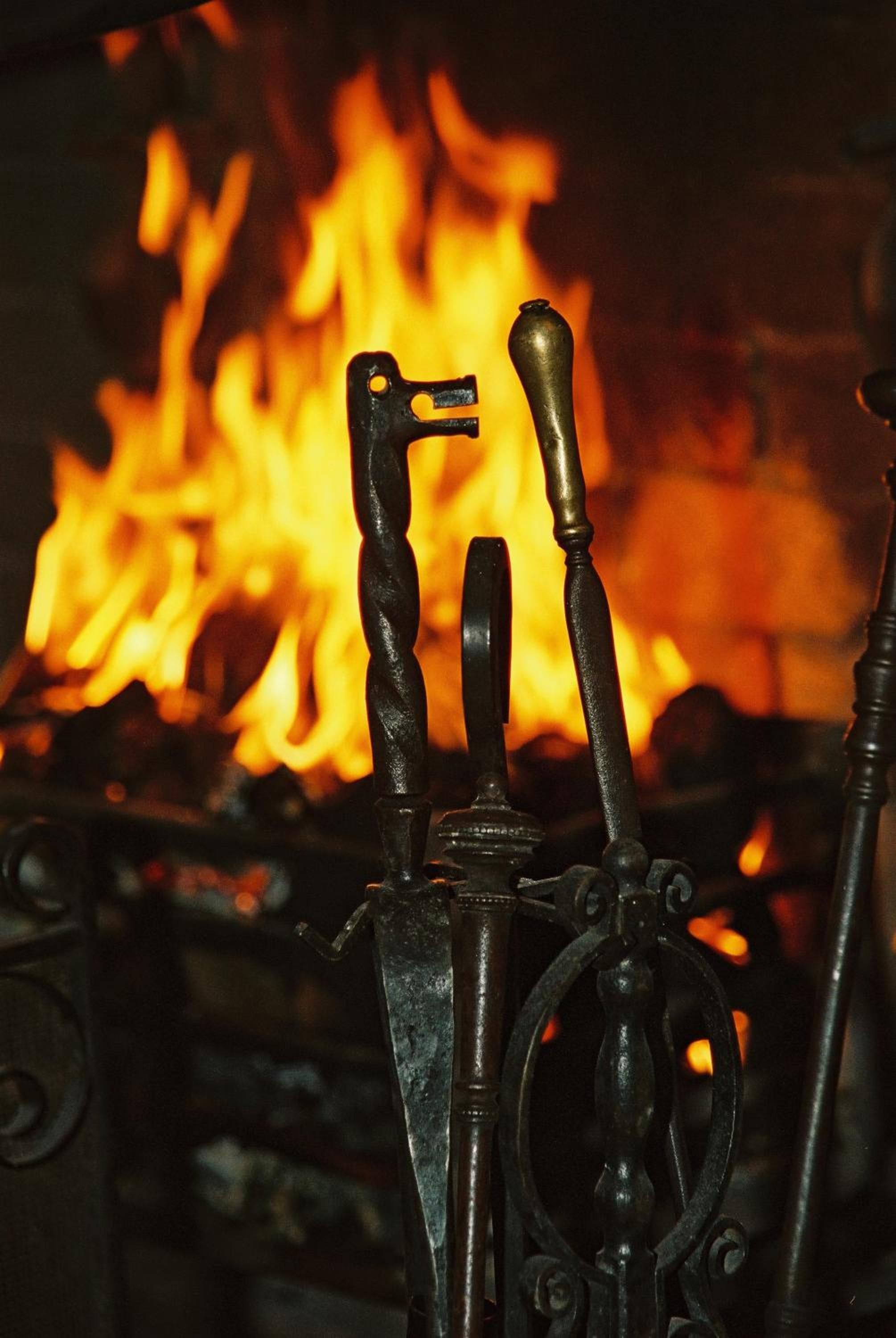 A close-up of a metal structure with a keyhole and a handle, set against a background of a fire.