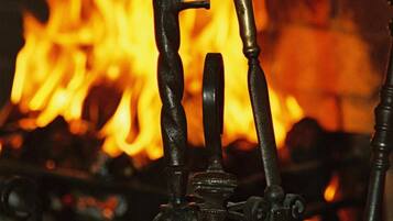 A close-up of a metal structure with a keyhole and a handle, set against a background of a fire.