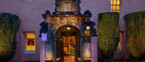 Un bâtiment rose avec une enseigne indiquant la réception, un escalier et une porte donnant accès à l’intérieur.