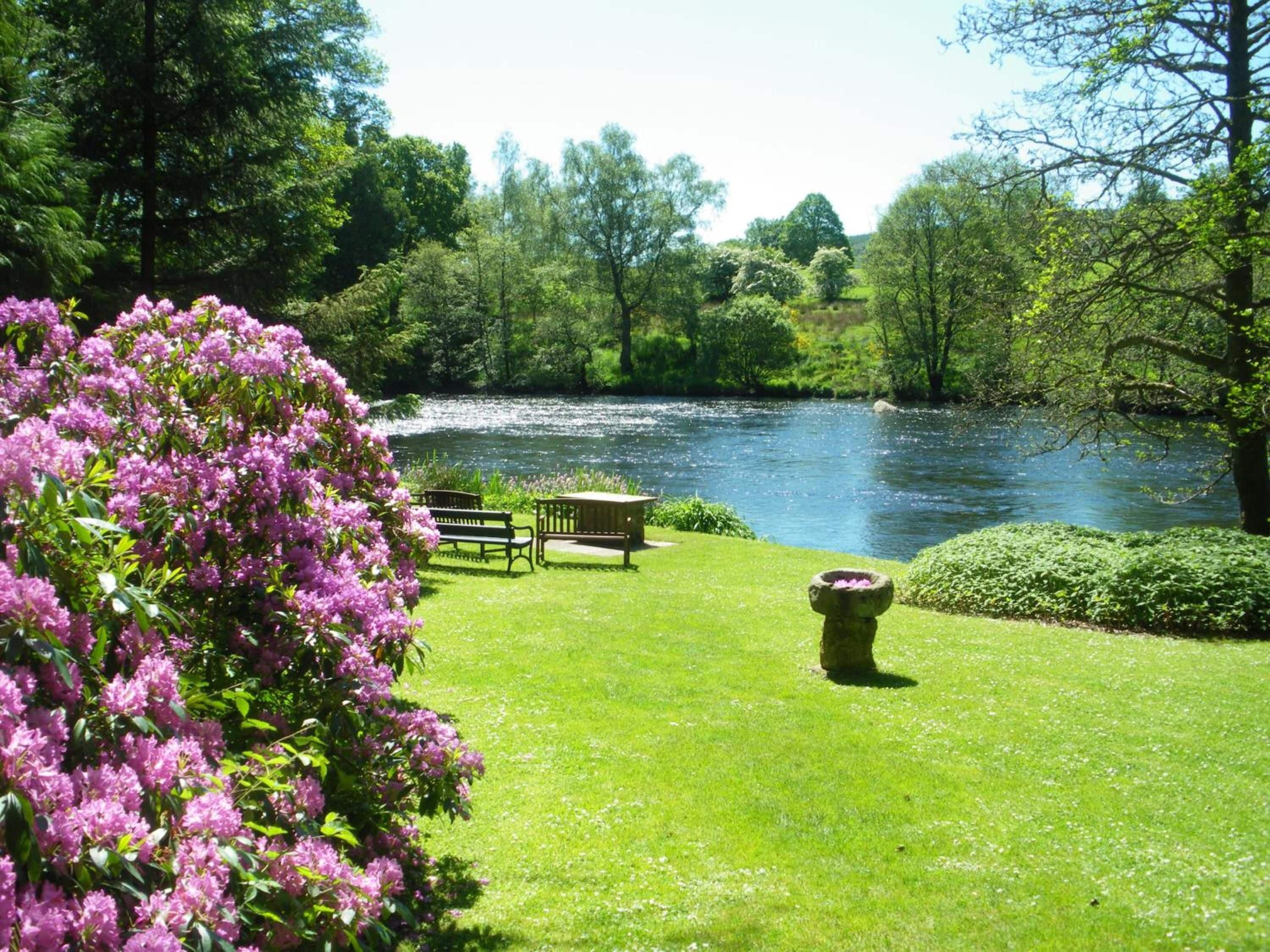 A riverside park with a bench and a flower bed.