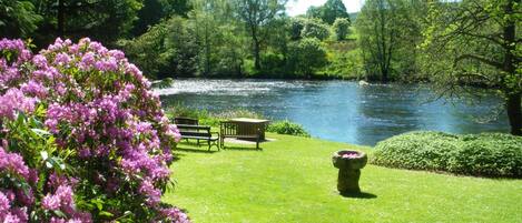 A riverside park with a bench and a flower bed.