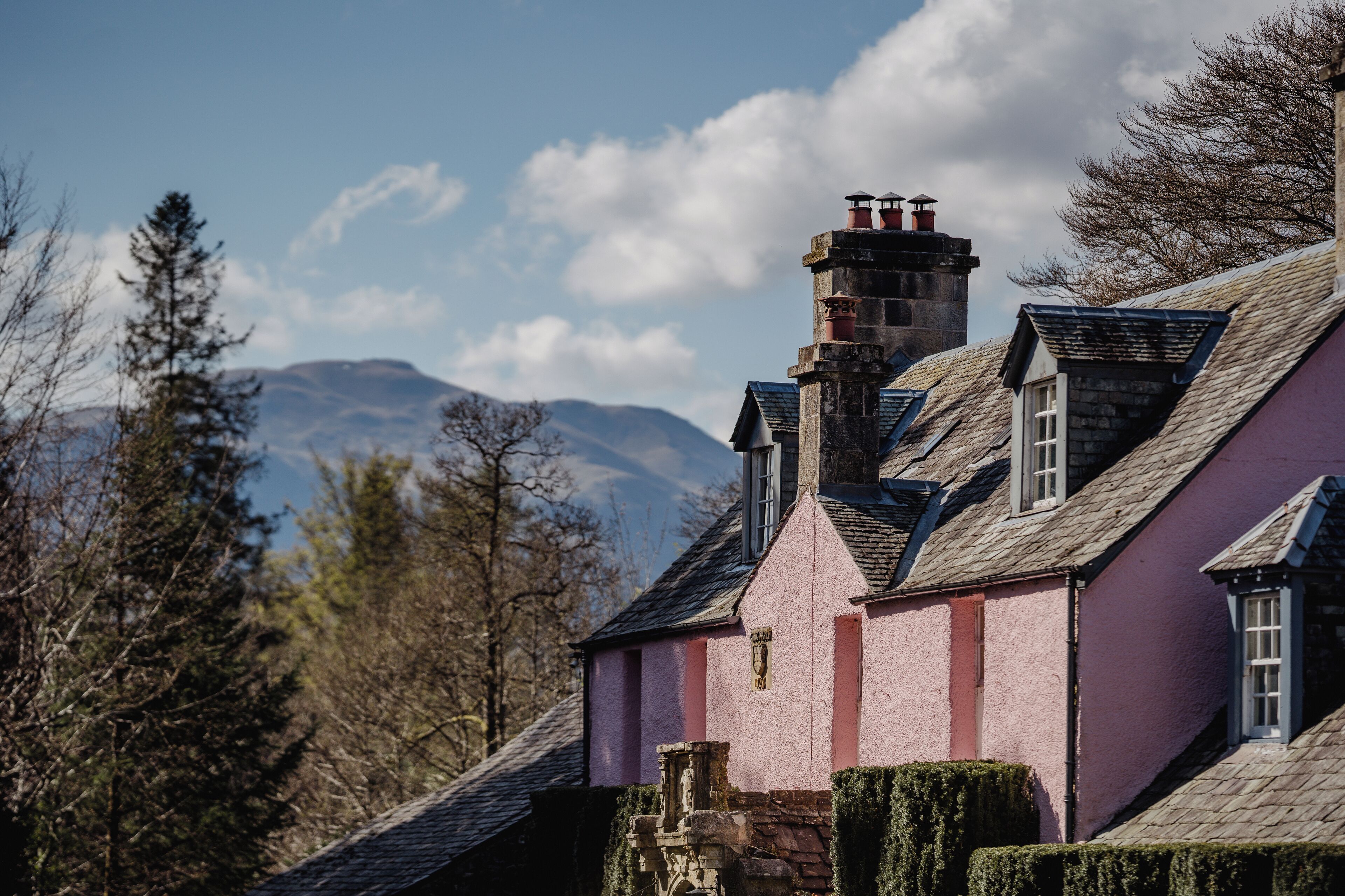 Un bâtiment rose avec une cheminée en pierre et une fenêtre.