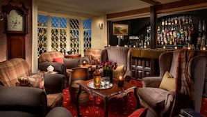 A cozy room with a bar area, a fireplace, and a large clock on the wall.