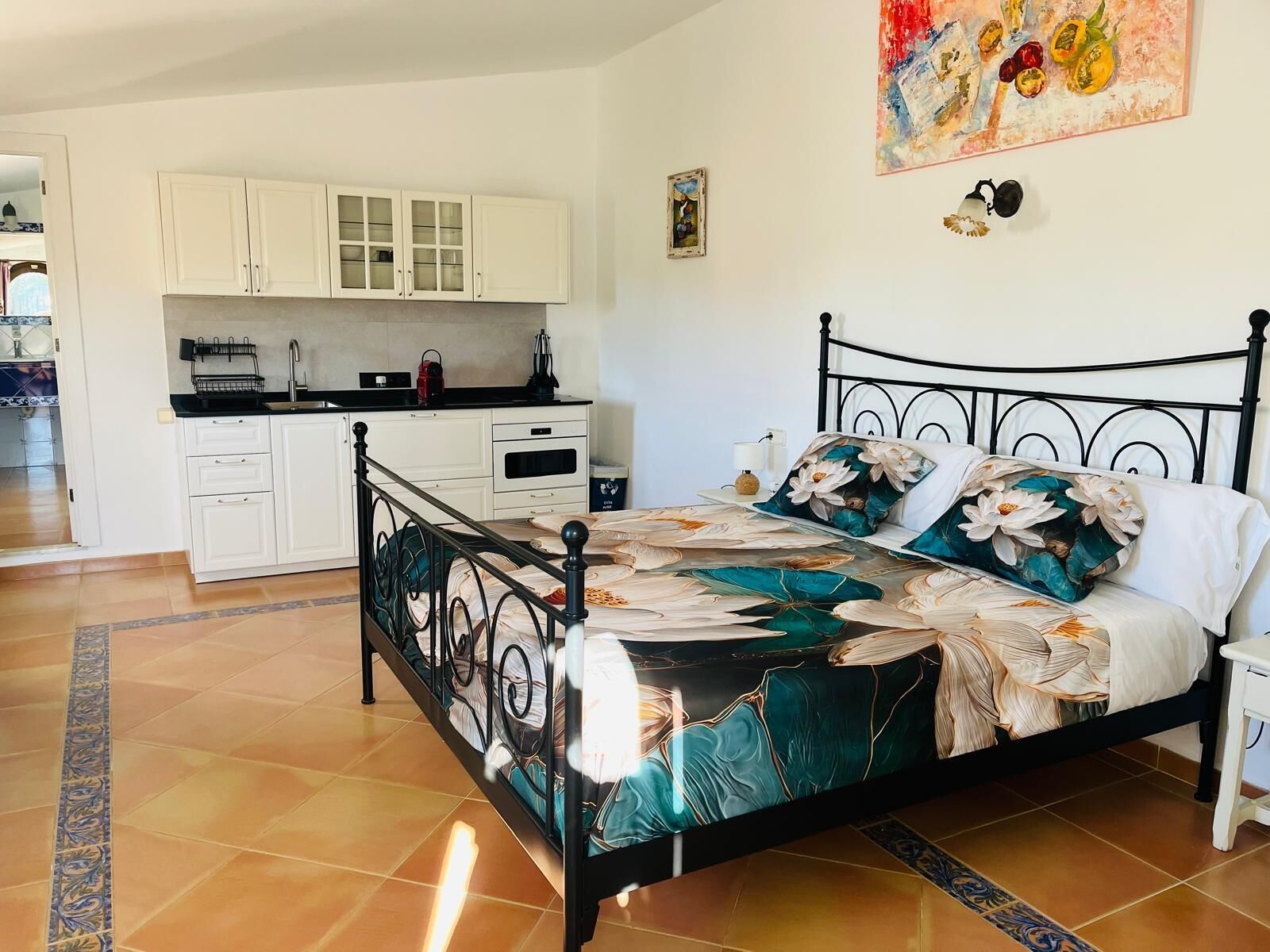 Ein Schlafzimmer mit einem Bett, einem Nachttisch und Blick zur Küche.