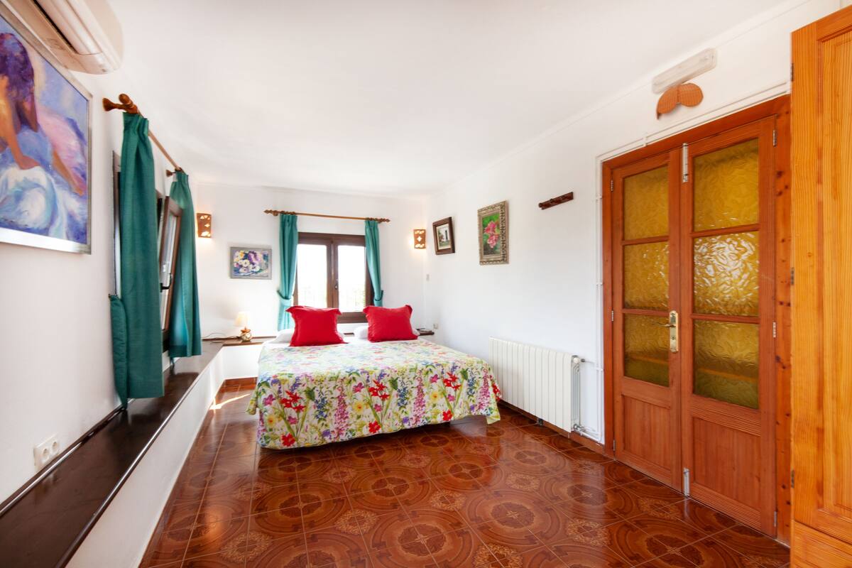 A bedroom with a bed, curtains, a radiator, and a wooden door.