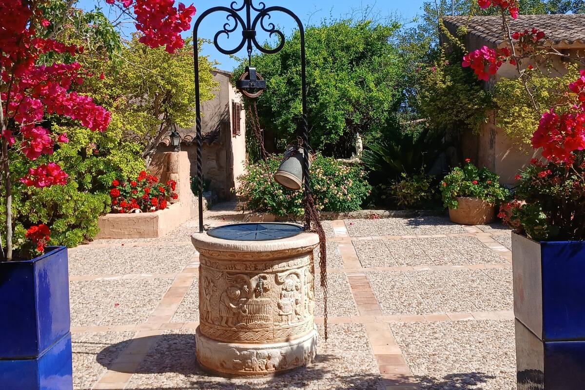 A courtyard with a fountain, stone pathway, and potted plants.