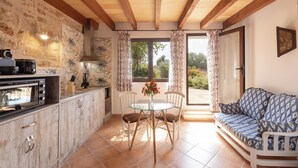 A kitchen with a built-in oven, a dining table with chairs, and a sofa. - Finca Son Marimon - Adults Only (Santanyi)