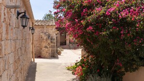 A narrow stone pathway flanked by walls with hanging lanterns and blooming pink bougainvillea. - Finca Son Marimon - Adults Only (Santanyi)