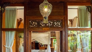 A traditional room with a bed, a hanging lamp, and a view of the outdoors. - Gusde Tranquil Villas by EPS (Ubud)
