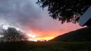 Ein Sonnenuntergang über einer hügeligen Landschaft mit einem Holzzaun im Vordergrund.