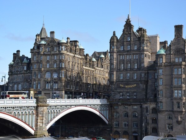 A historic building with multiple arches and a bridge in the foreground.