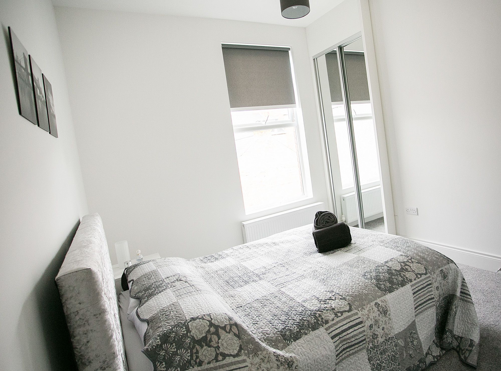 Un dormitorio con cama, ventana y espejo.