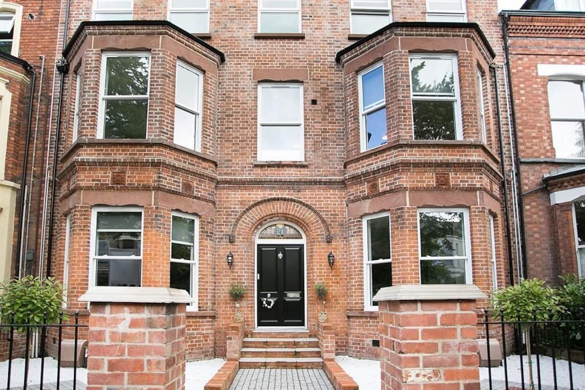 A brick building with a black front door, multiple windows, and a small entrance with steps.