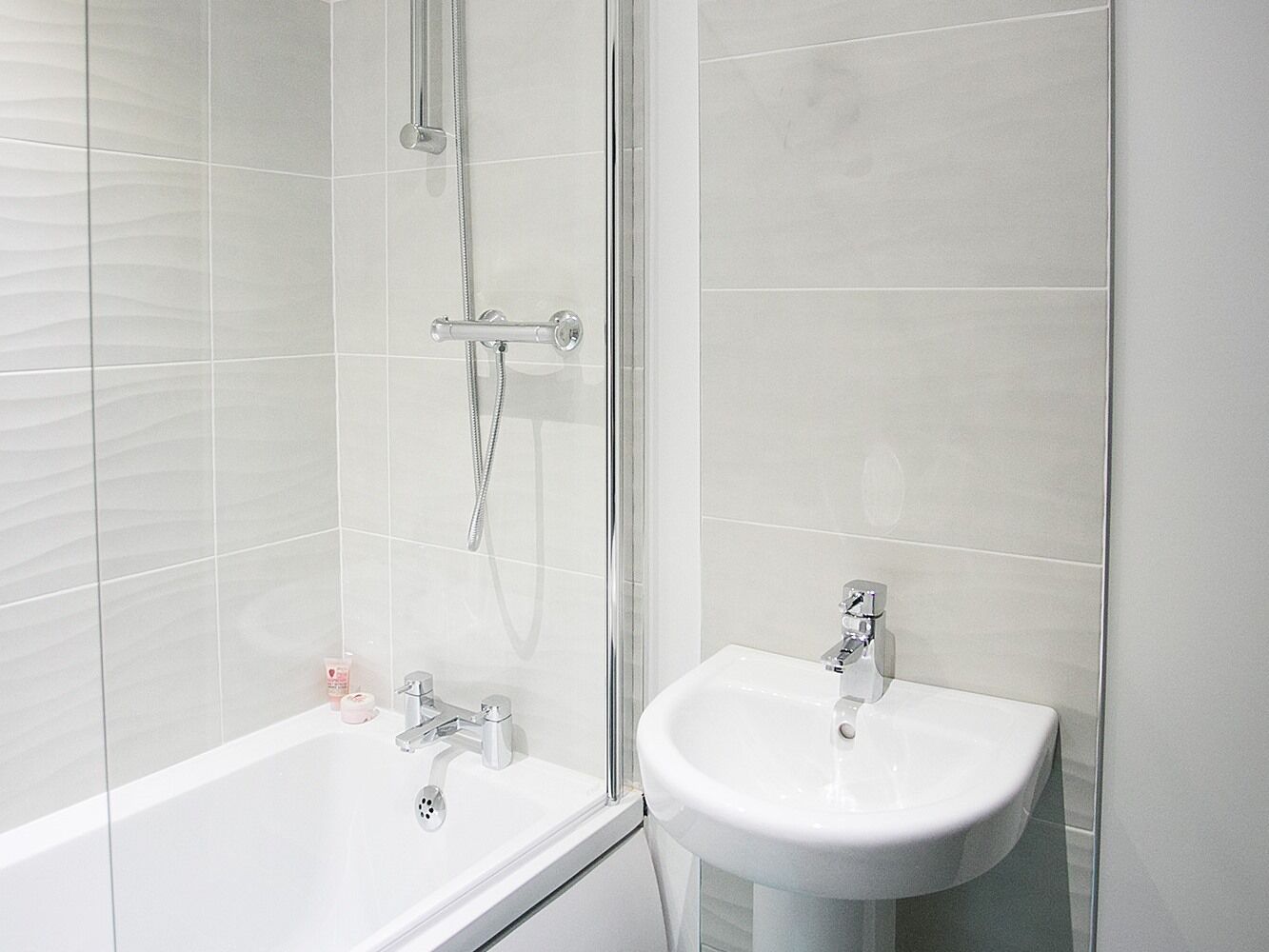 Une salle de bain moderne avec une douche à parois de verre, une baignoire blanche et un lavabo blanc.