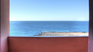 A view of the ocean from a window with a red wall.