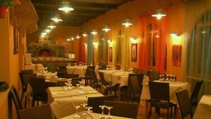 A restaurant with multiple tables and chairs, warm lighting, and a rustic decor.