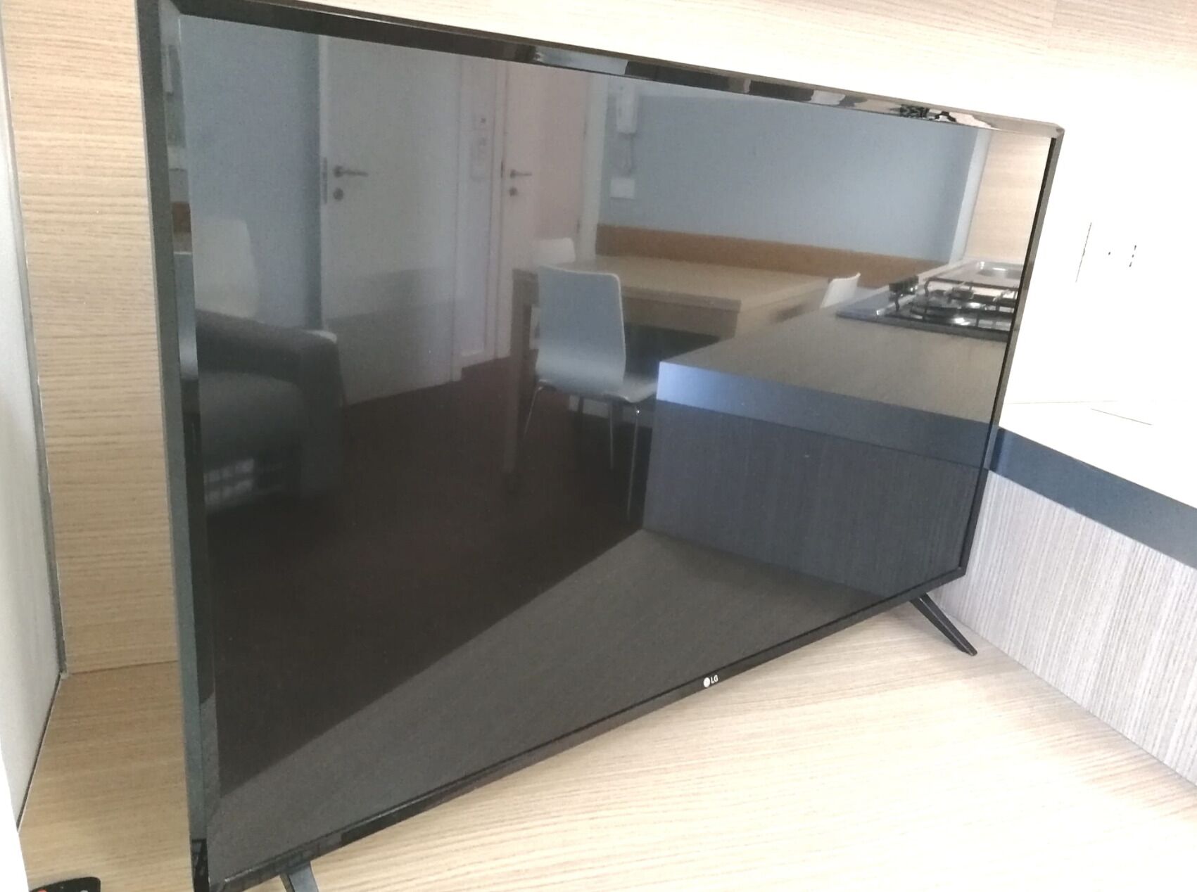 Quarto de hotel moderno com uma televisão de tela grande, uma escrivaninha de madeira e uma cadeira.