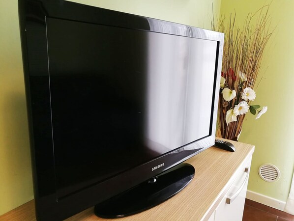 A Samsung TV on a wooden stand against a green wall.