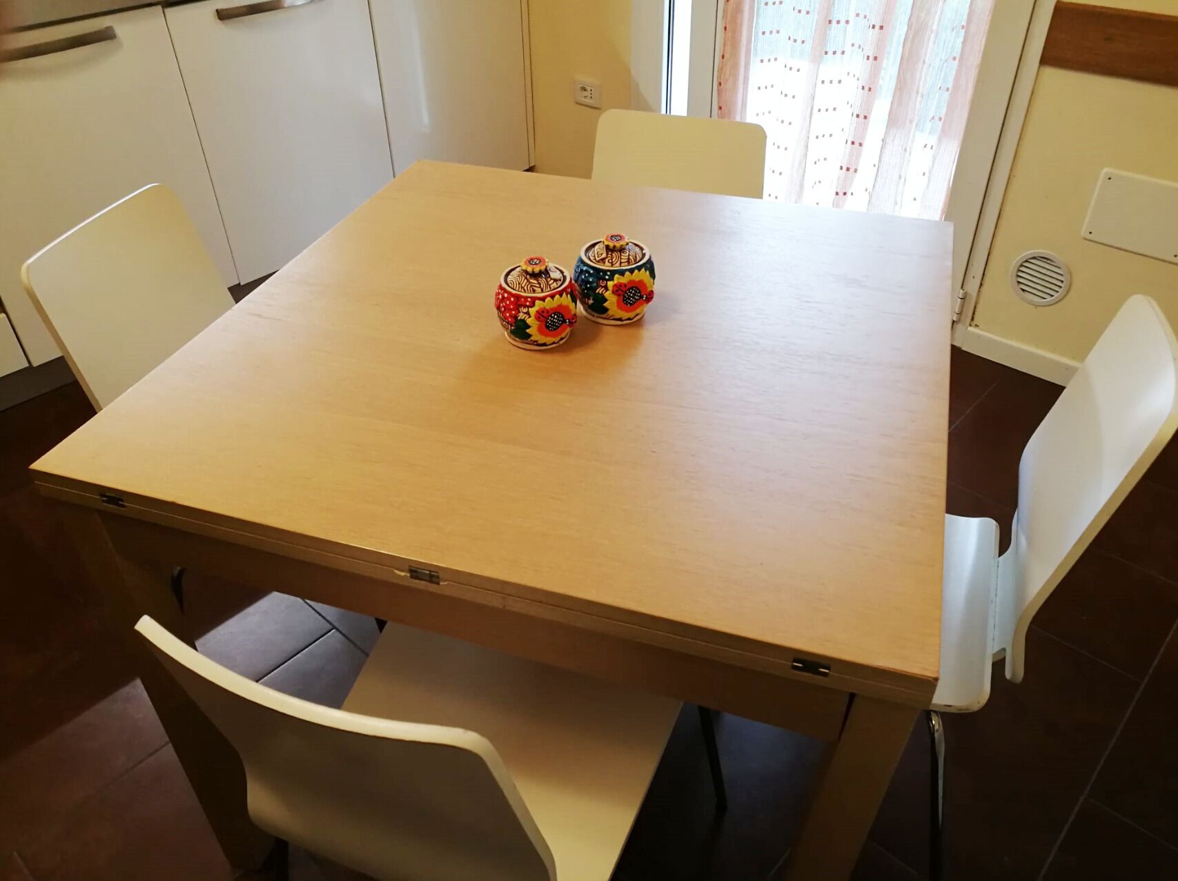 A wooden dining table with two colorful ceramic cups.