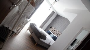A modern bedroom with a bed, a bedside table, a mirror, and a window with curtains. - De Rohan B&B (Zebbug)