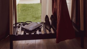 A room with a wooden bench, a hanging dress, and a pair of shoes. - De Rohan B&B (Zebbug)