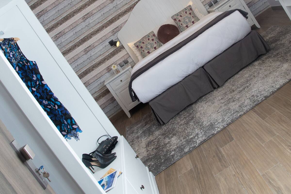 Une chambre à coucher moderne avec un lit, des tables de chevet, une petite table et un luminaire suspendu.