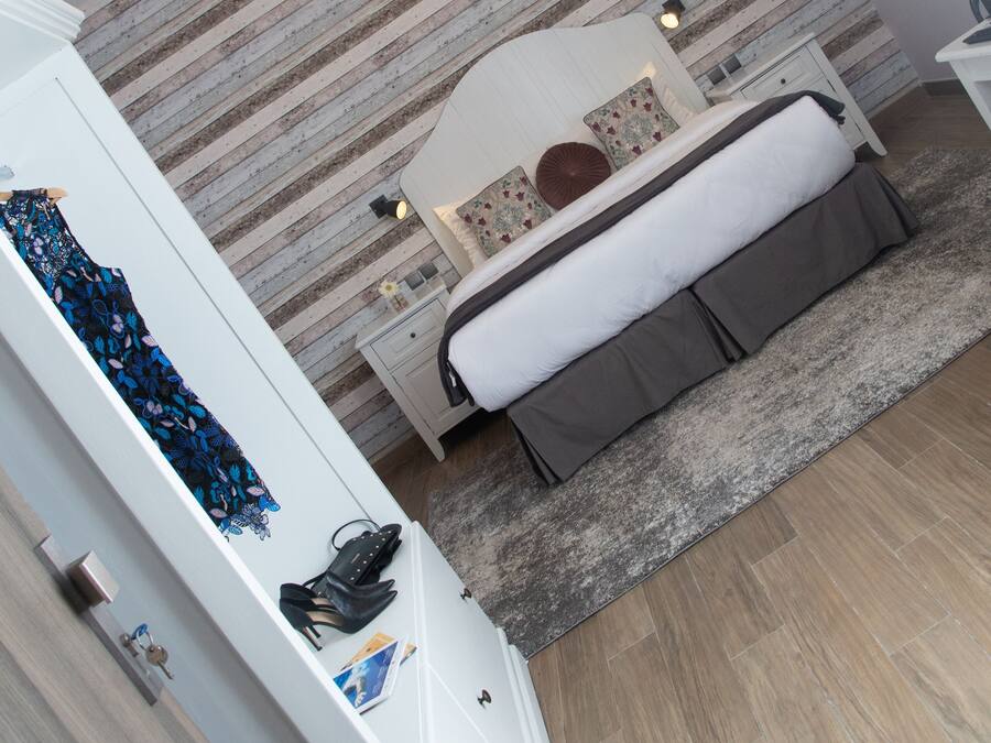 Een moderne slaapkamer met een bed, nachtkastjes, een hanglamp en een nachtkast.