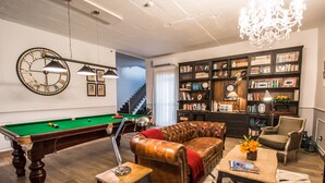 A living room with a pool table, leather sofa, bookshelf, and a chandelier. - De Rohan B&B (Zebbug)