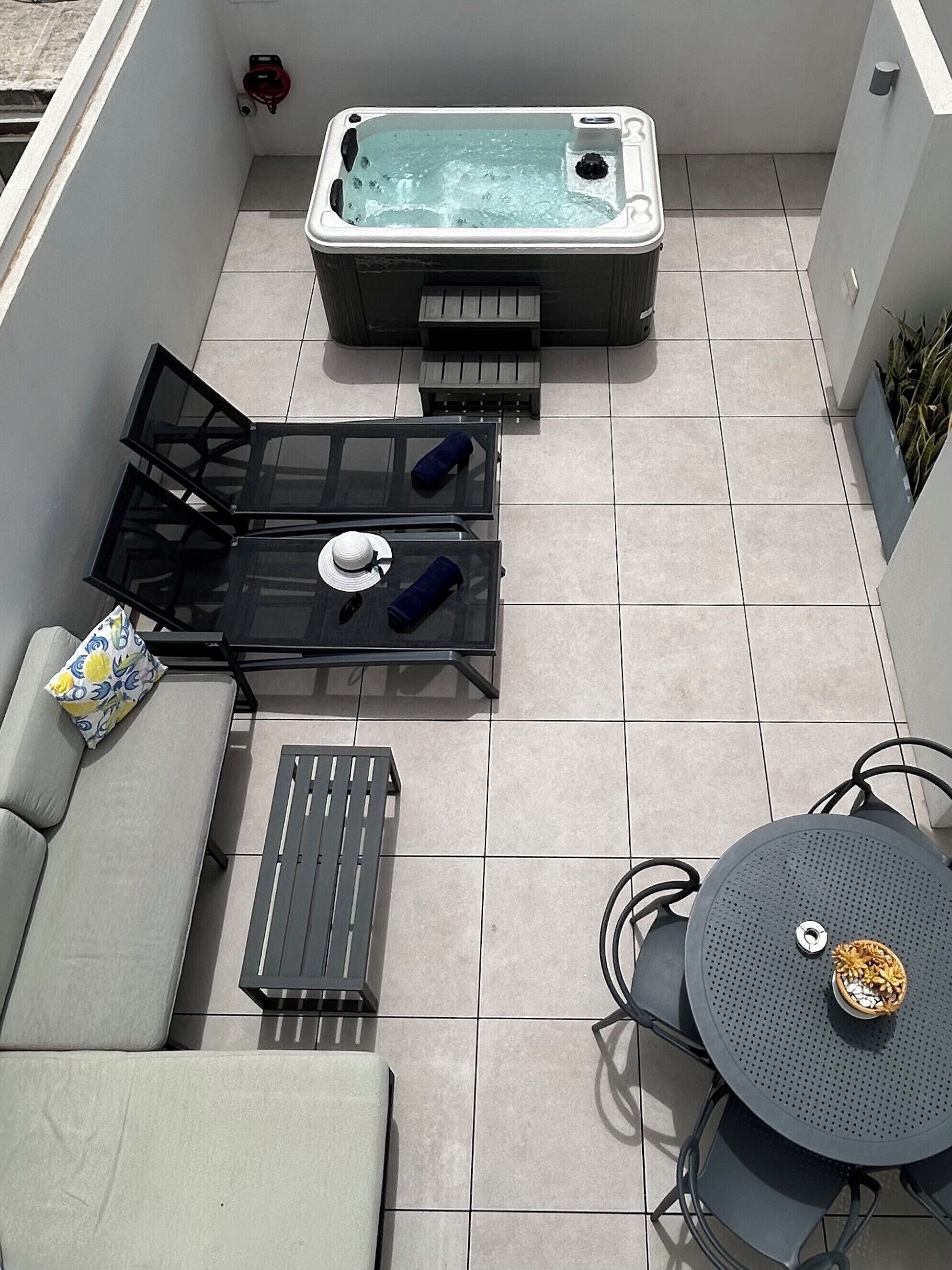 Een dakterras met een hottub, een bank, een tafel en stoelen.