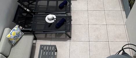 Un patio en la azotea con un jacuzzi, un sofá, una mesa y sillas.