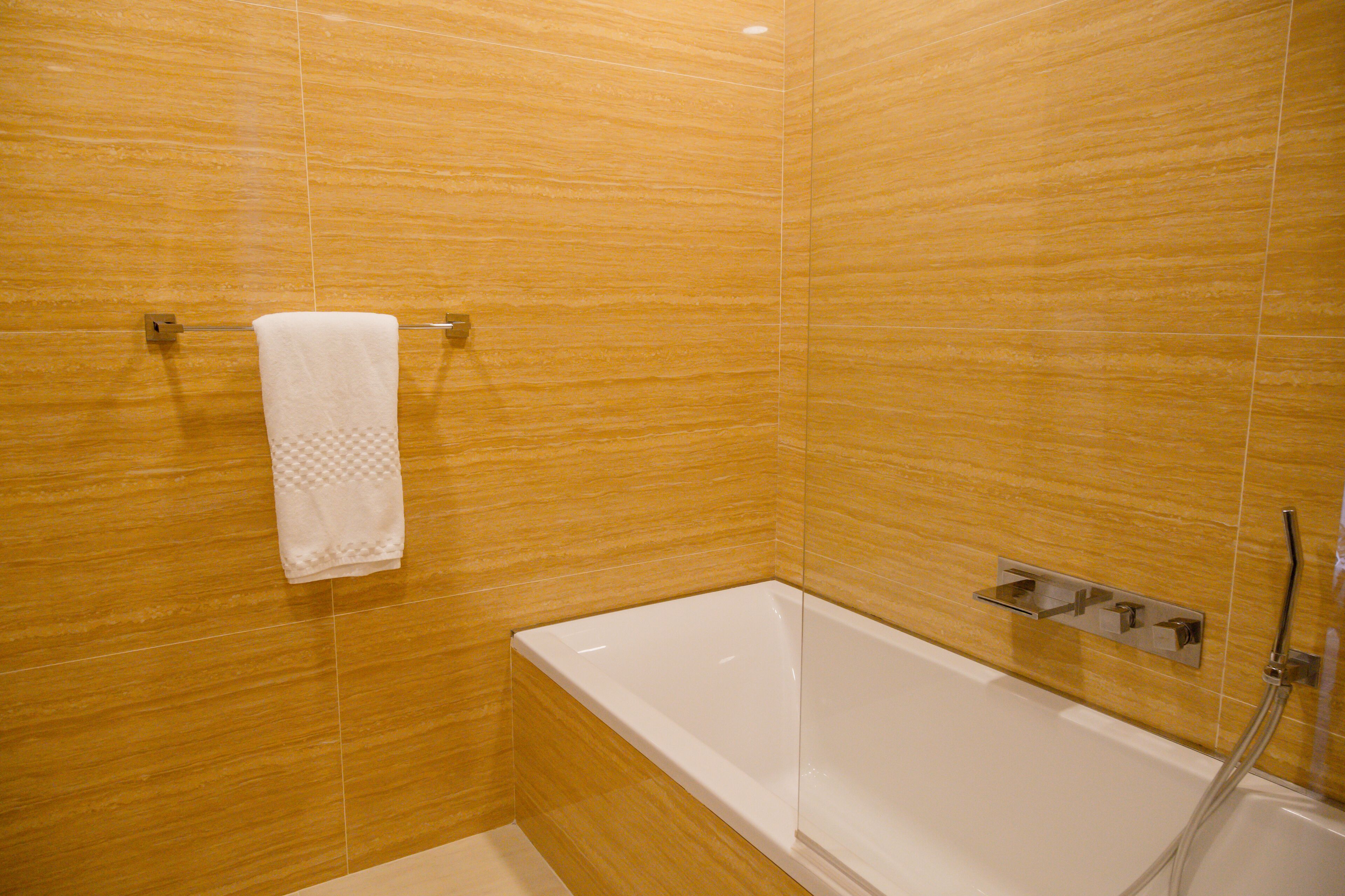 A bathroom with a white bathtub, a towel hanging on a rack, and a shower control panel.