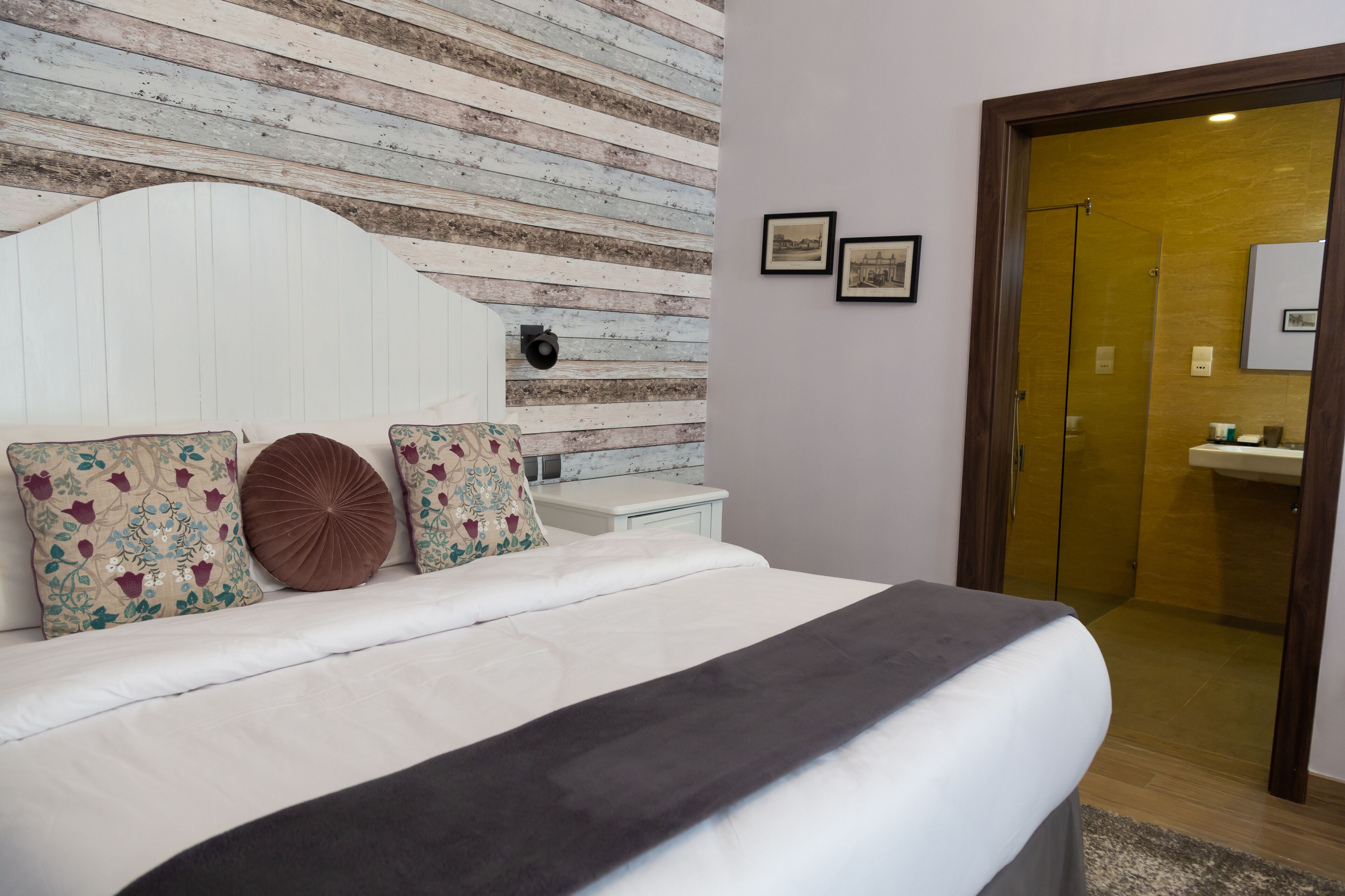 A bedroom with a bed, a nightstand, and a wooden headboard. There is a door leading to a bathroom.