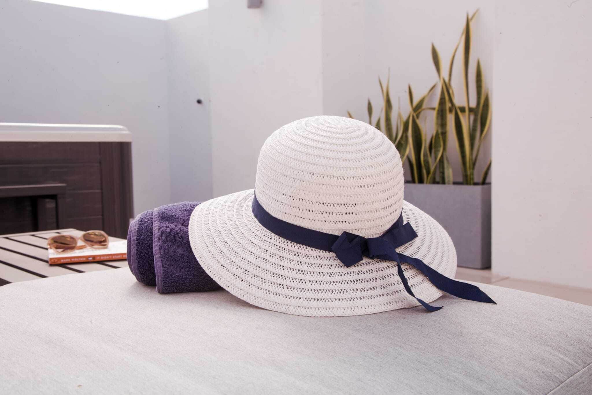 A white woven hat with a dark ribbon on a light-colored sofa.